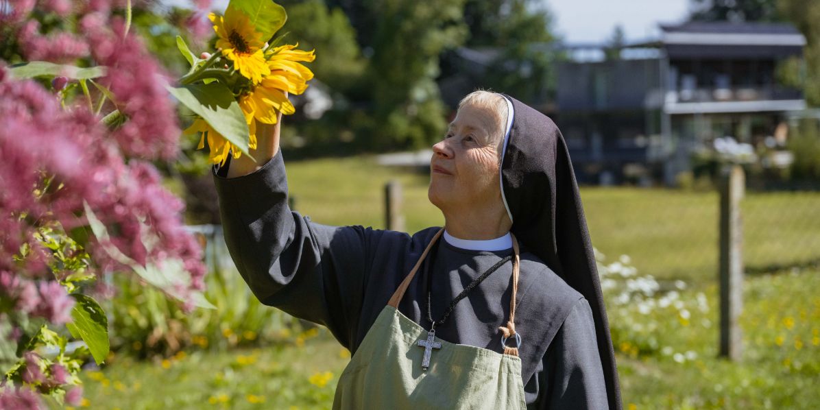 Eine Schwester im Garten betrachtet eine Sonnenblume